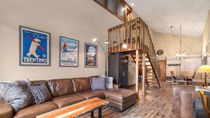 A modern living room with a brown leather sofa, a wooden bench, and a staircase leading to an upper level. - Fp300 Foxpine Inn 2 Bedroom Condo (Copper Mountain)