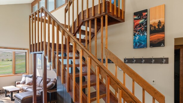A spacious living area with a wooden staircase, a couch, and a view of the outdoors. - Fp300 Foxpine Inn 2 Bedroom Condo (Copper Mountain)