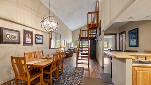 A spacious kitchen with a wooden island, a dining area with a large table and chairs, and a staircase leading to an upper level. - Fp300 Foxpine Inn 2 Bedroom Condo (Copper Mountain)