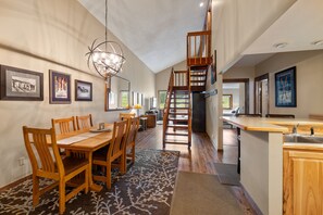 A spacious kitchen with a wooden island, a dining area with a large table and chairs, and a staircase leading to an upper level.