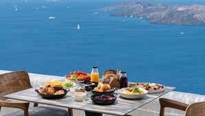 Una mesa con alimentos para el desayuno y vista al mar.