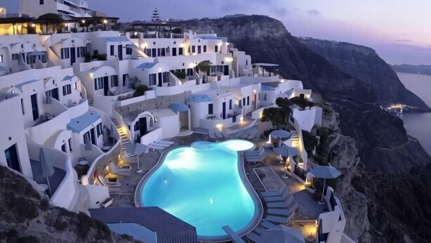 Un hôtel situé sur la côte, doté d’une piscine, de bâtiments blancs et offrant une vue sur la mer.