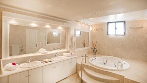 Une salle de bain moderne avec un grand miroir, deux lavabos, une baignoire et une fenêtre.