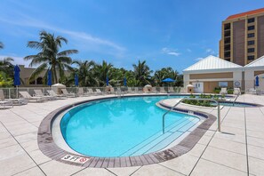 A pool area with a 3 FT no diving sign, lounge chairs, and palm trees.