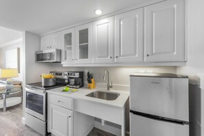 A modern kitchen with white cabinets, stainless steel appliances, and a built-in microwave.