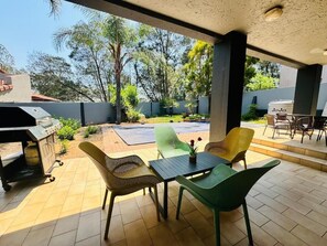 An outdoor patio with a grill, chairs, and a table. - Villa Picasso- 1 Bed Villa (Johannesburg)