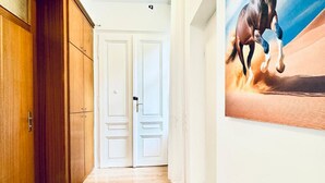 A hallway with wooden doors and a white door, a painting of a horse on the wall, and a light-colored floor. - Cozy Stay in Shared Apt  Short Walk to Westbahnhof (Vienna)