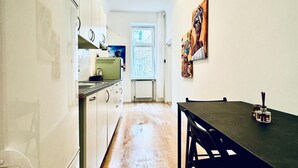 A narrow hallway with a kitchen area on one side, a dining table with chairs, and a window with a view. - Cozy Stay in Shared Apt  Short Walk to Westbahnhof (Vienna)