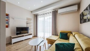 Una sala de estar moderna con una televisión de pantalla plana, un sofá, una mesa de centro y un equipo de aire acondicionado.