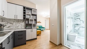 A modern kitchen with marble countertops, grey cabinets, and a wooden floor. - Luma One-bedroom Penthouses by Kondo Stays (Tiranë)