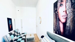 Ein modernes Schlafzimmer mit einer Couch, einem Bett, einem kleinen Tisch und einem großen Poster an der Wand.