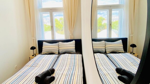 Une chambre avec un lit, deux tables de chevet et une fenêtre avec des rideaux.