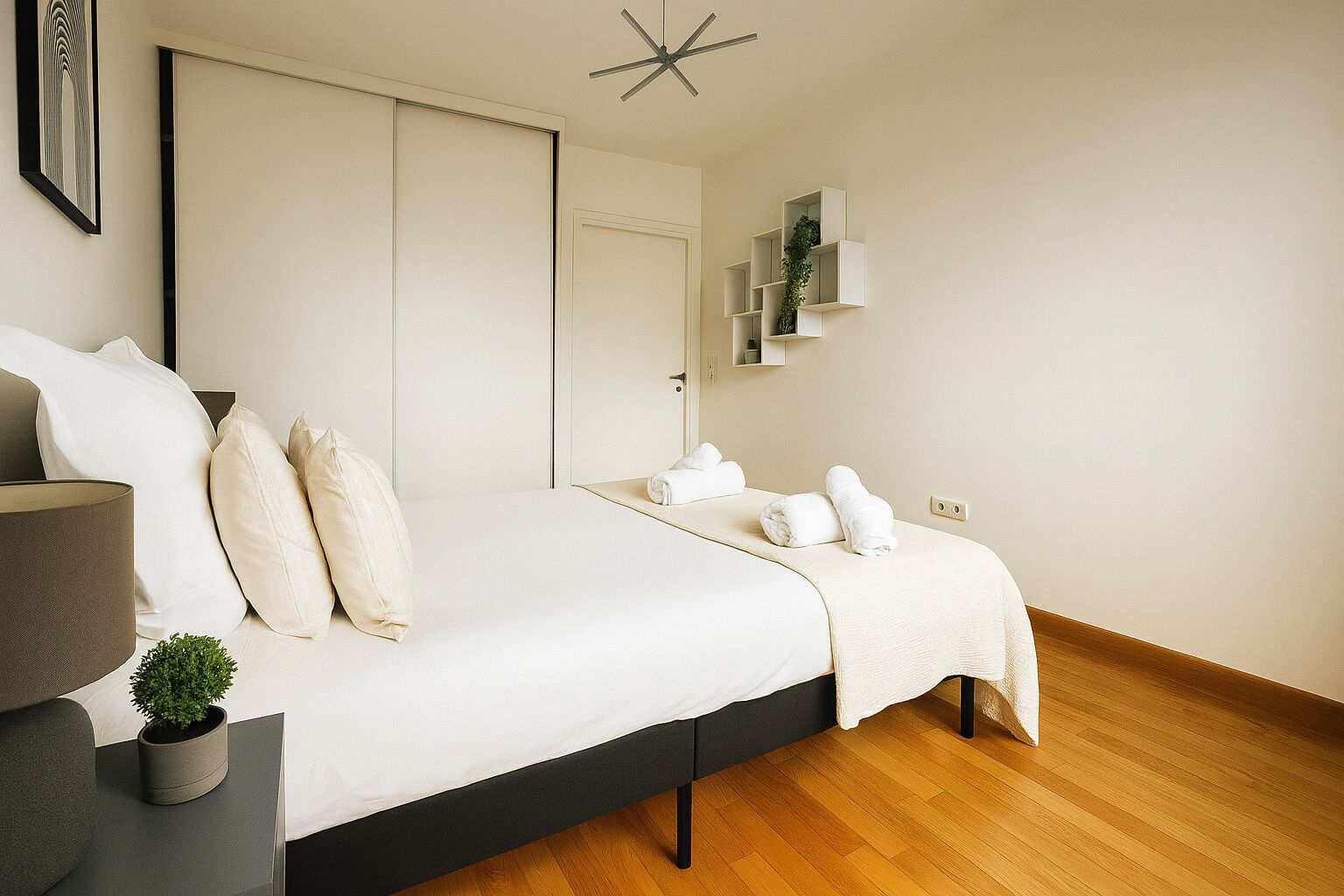 A modern bedroom with a bed, bedside tables, a potted plant, and a wall-mounted shelf.