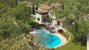 A large house with a swimming pool surrounded by trees.