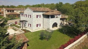 A stone building with a tiled roof, a central courtyard, and a surrounding garden.