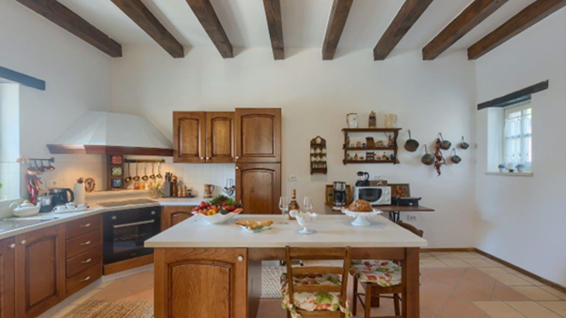 A kitchen with wooden cabinets, a central island, and a dining area with chairs.