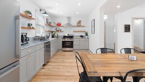 Una cocina moderna con armarios grises, una mesa de comedor de madera y electrodomésticos integrados.