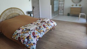 A bedroom with a bed, a bedside table, a mirror, a wardrobe, and a bathroom visible through an open door. - Villa in the southern moors, 10 minutes from the ocean (Magescq)