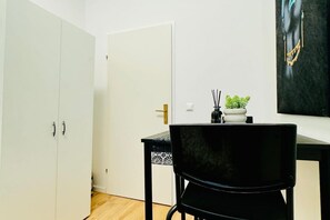 A room with a black chair, a white door, and a painting on the wall.