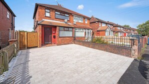 A two-story brick house with a paved driveway and a wooden fence.