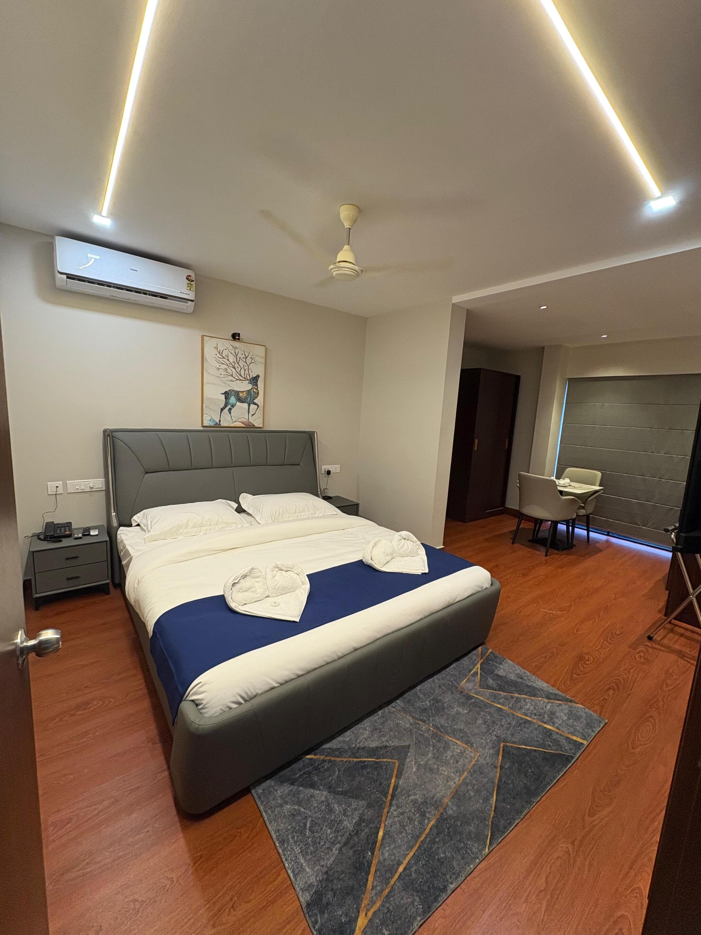 A modern hotel room with a large bed, a desk, and a dining area.
