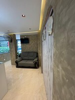 A modern living area with a sofa, a mounted television, and a fan.