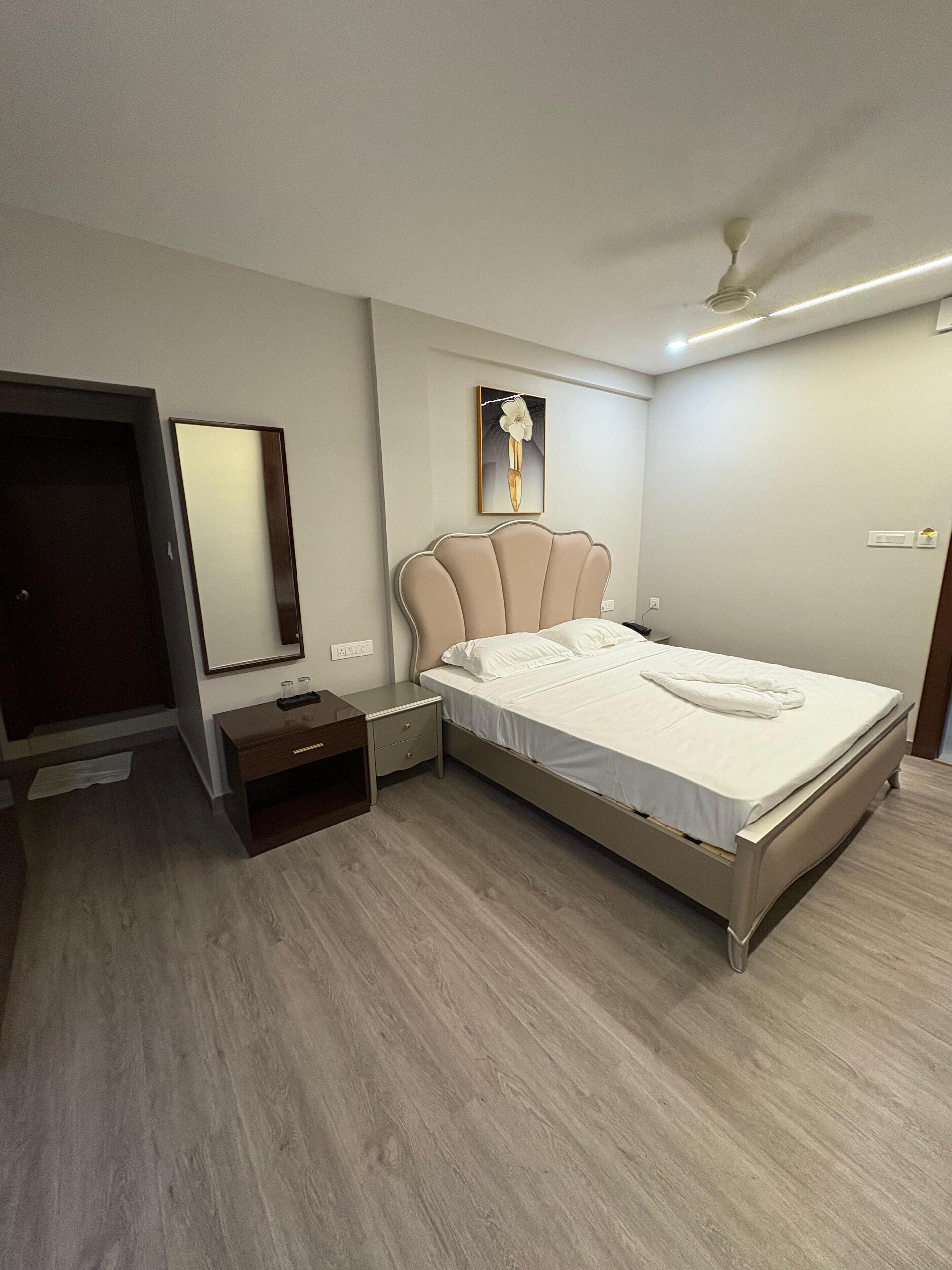 A bedroom with a bed, bedside table, nightstand, and a ceiling fan.