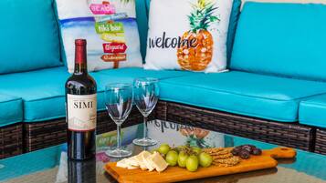 Una botella de vino Simi, dos copas, una tabla de madera con queso, uvas y galletas sobre una mesa de vidrio.