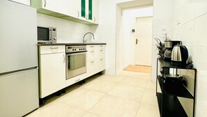 A compact kitchen with white cabinets, a microwave, an oven, and a coffee maker.