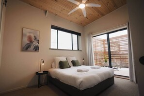 Une chambre à coucher avec un lit, un ventilateur de plafond, une fenêtre et une vue sur l’extérieur.