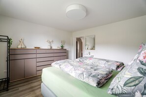 A bedroom with a bed, dresser, mirror, and a small bathroom with a sink. - Holiday Apartment Waldrose with Mountain View, Private Terrace and Wi-Fi (Oberharmersbach)