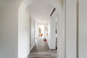 Un couloir doté d’un plafond en arc de cercle, de murs blancs et d’un plancher en bois.