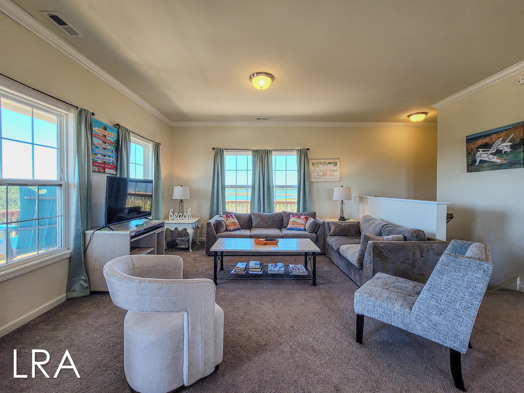 A spacious living room with a large window, a flat-screen TV, a coffee table, and multiple seating options including a sofa and armchairs.