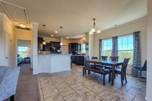 A spacious kitchen with a central island, dining table, and chairs. There is a separate dining area with a window and curtains. - Sound Escape-NEW!-Stunning Sound Views! (North Topsail Beach)