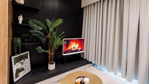 Una sala de estar moderna con chimenea, televisor y planta en maceta.