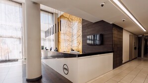 Una moderna recepción con un muro decorativo de madera, un televisor de pantalla plana y un logo en la barra.