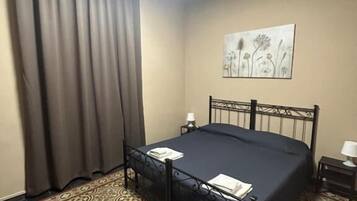 A hotel room with a bed, a nightstand, a lamp, a painting on the wall, and patterned carpet.