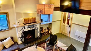 Ein gemütliches Wohnzimmer mit Kamin, Fernseher und einer bequemen Sitzecke.