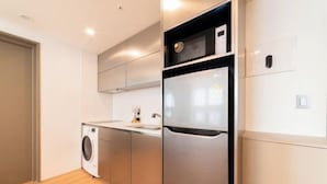 A modern kitchen with a stainless steel refrigerator, a built-in washing machine, and a countertop sink.