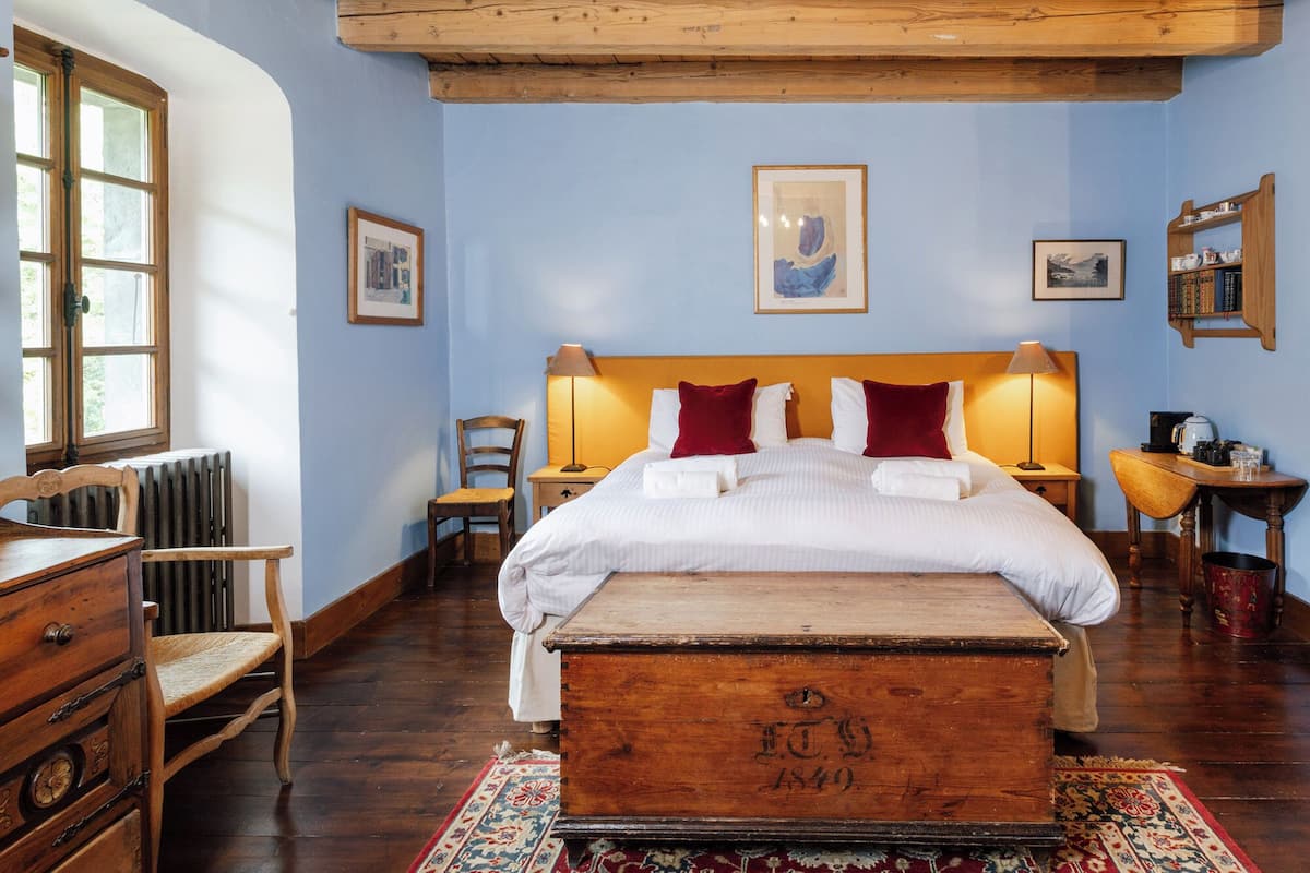 Una camera da letto con una testiera in legno, un letto grande, un baule in legno, una scrivania e una sedia.