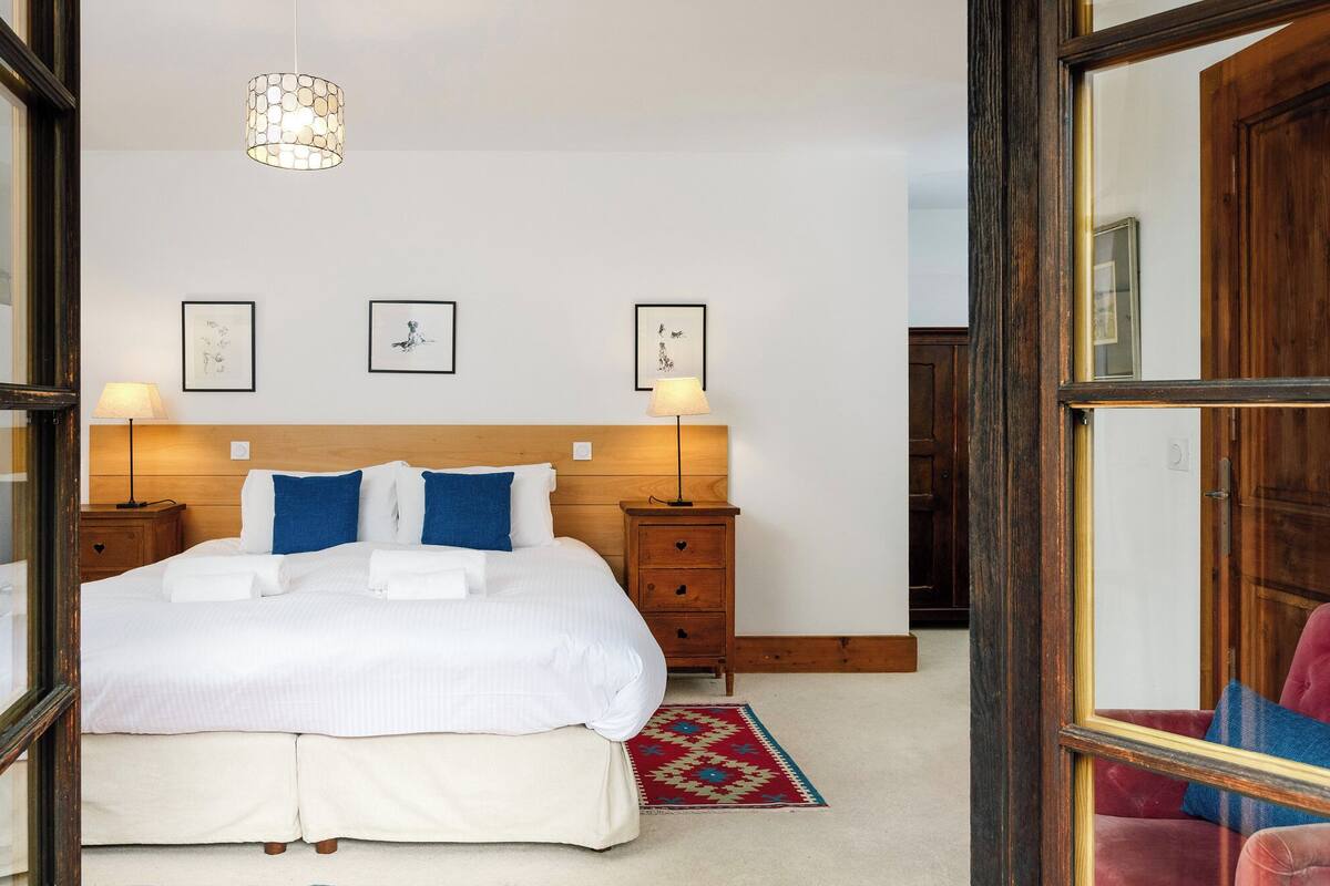 Una camera da letto ordinata con un letto grande, due comodini, un lampadario e quadri appesi al muro.
