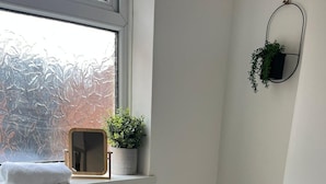 Ein Badezimmer mit Toilette, Waschbecken und einem Fenster mit Blick auf Bäume.