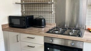 Eine Küche mit Mikrowelle, Gasherd, Backofen und gefliestem Fliesenspiegel.