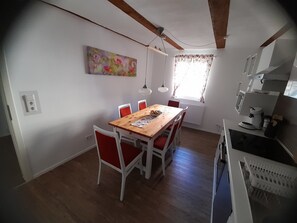 Ein Essbereich mit einem Holztisch und roten Stühlen, einem Bild an der Wand und einem Fenster mit Vorhängen.