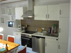 Eine moderne Küche mit Edelstahlgeräten, weißen Schränken und einem Holztisch.