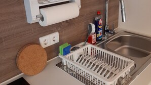 Une cuisine équipée d’un distributeur de serviettes en papier encastré, d’un évier en acier inoxydable et d’un égouttoir.