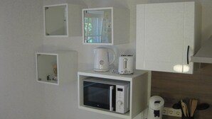 Une cuisine équipée d’un four à micro-ondes, d’un grille-pain et d’une machine à café, le tout posé sur le plan de travail.