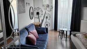A modern living room with a blue sofa, a dining table, and a chandelier. - Amber Hostel Szlak (Kraków)