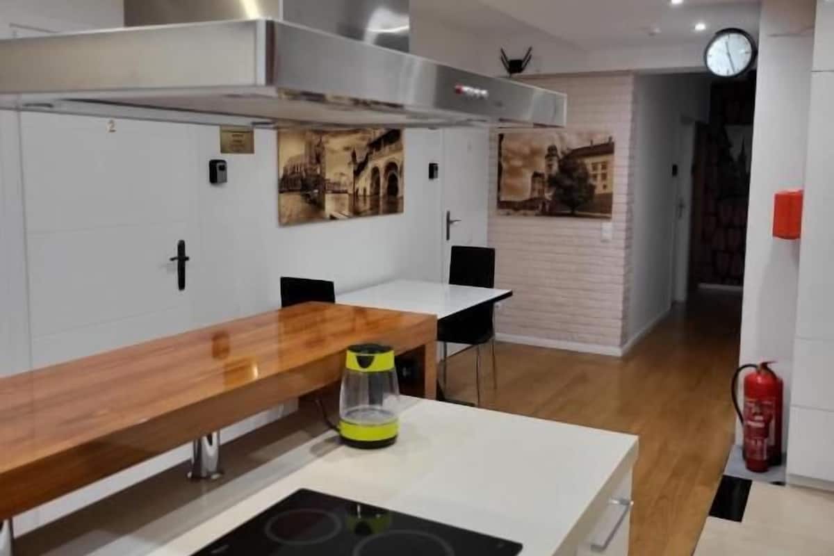 A modern kitchen with a wooden countertop, a black induction cooktop, and a yellow kettle.