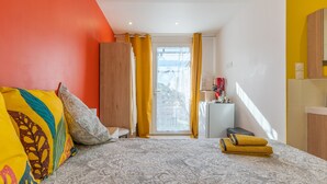 A hotel room with a bed, a desk, a small refrigerator, and a view of the outside. - Studio Apartment 'La Dolce Vita 2' with Shared Pool, Private Terrace and Air Conditioning (Lambesc)